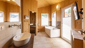 A wooden cabin bathroom with a large bathtub, a sink, and a mirror.