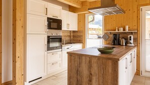 A modern kitchen with white cabinets, stainless steel appliances, and a wooden island.