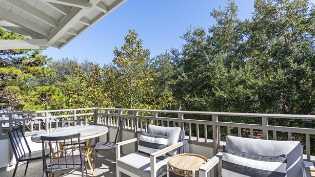 Ein Balkon mit Gartenmöbeln, darunter ein Tisch, Stühle und eine Sitzecke, umgeben von einer weißen Brüstung.