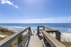 A wooden boardwalk leading to a beach with umbrellas. - Beach Cottage | Seacrest | Private Beach Access (Seacrest)