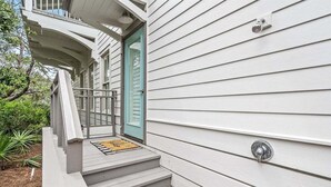 Ein Haus mit einer Veranda, einer blauen Tür und einer kleinen Stufe, die zum Eingang führt.