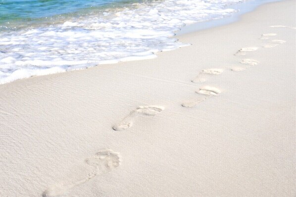 A sandy beach with footprints leading towards the water.