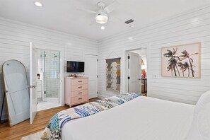 A bedroom with a bed, a television, a wardrobe, a door, and a ceiling fan.