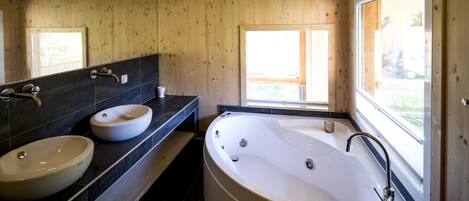 A modern bathroom with two sinks, a bathtub, and a large window.