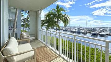 Un balcon donnant sur un port de plaisance, avec une balustrade blanche et un canapé agrémenté de coussins.