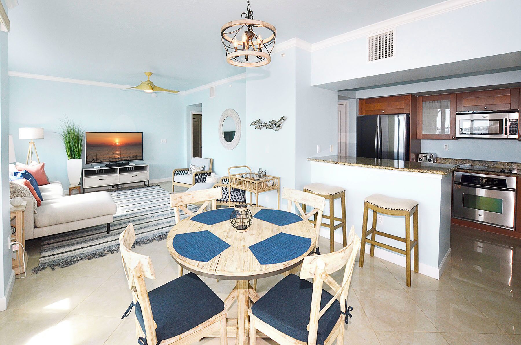 Un salon moderne comprenant un téléviseur, un canapé et un coin repas avec des chaises et une table.
