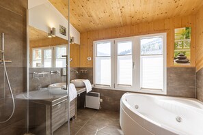 Une salle de bain moderne dotée d’une grande baignoire, d’une douche à parois de verre et d’un meuble-lavabo avec un évier et un miroir.