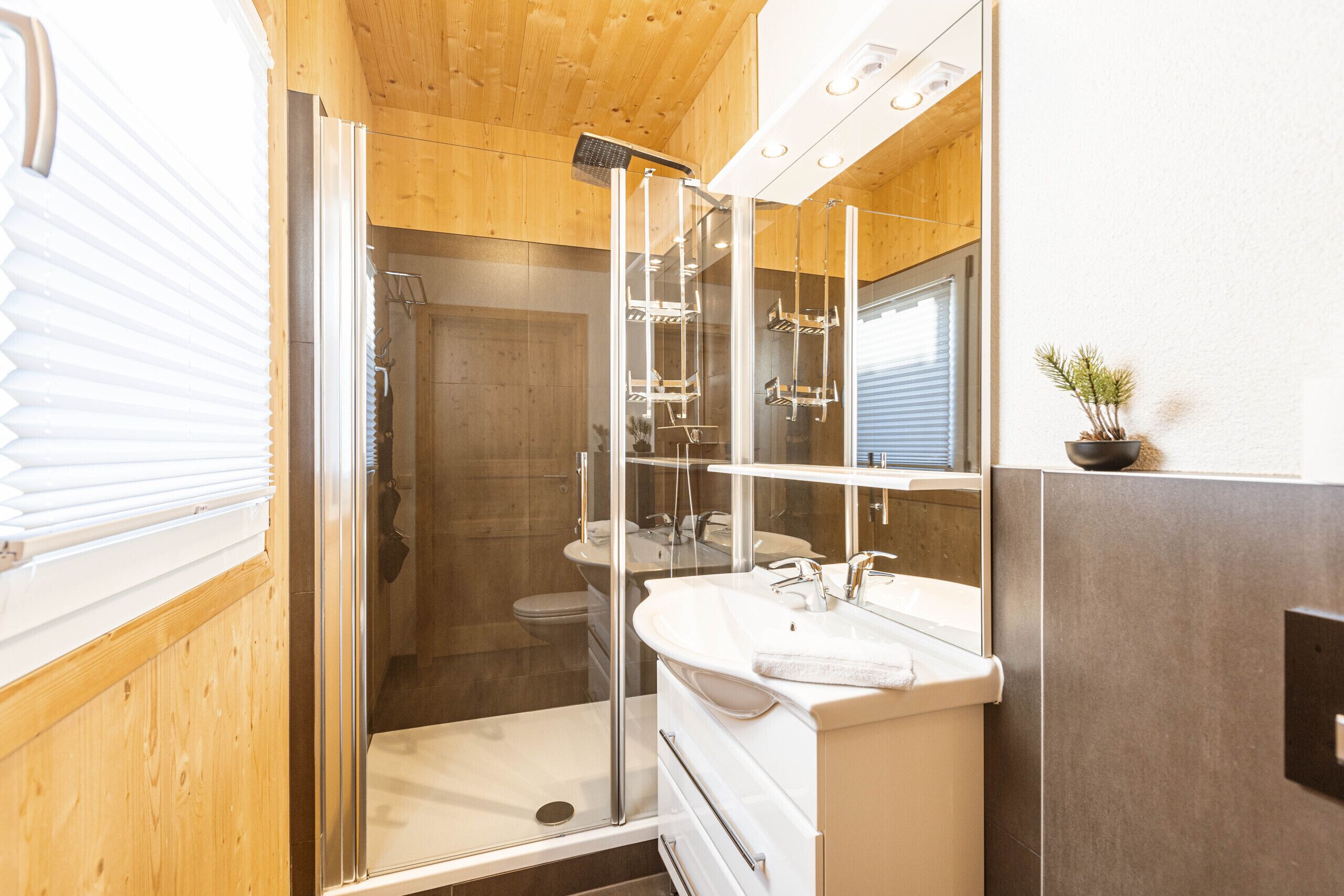 A modern bathroom with a glass-enclosed shower, a white sink, and a mirror above it.