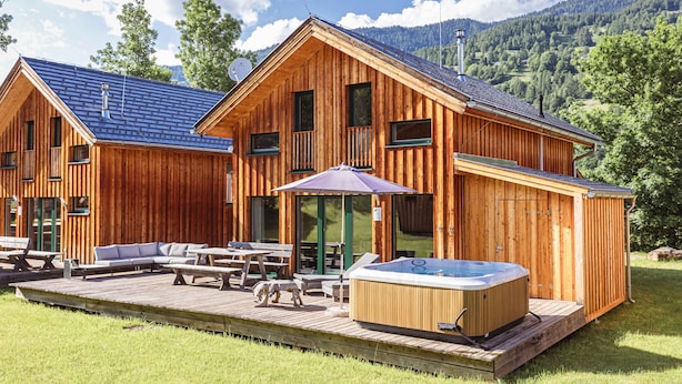 A wooden cabin with a hot tub, outdoor seating, and a deck.
