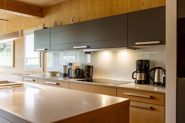 A modern kitchen with wooden cabinets, a stainless steel sink, and a coffee maker.