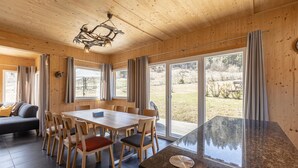 Puinen sisustus, jossa on ruokailutila, suuret ikkunat ja keittiötaso.