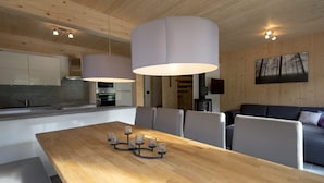 Una cocina moderna con armarios de madera, una mesa de comedor con candelabros y un sofá gris en un ambiente de sala acogedor.