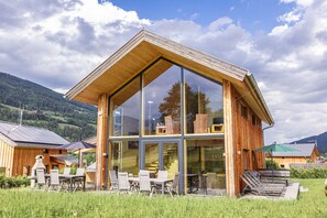 Un edificio moderno de madera con grandes ventanales y un comedor con terraza.