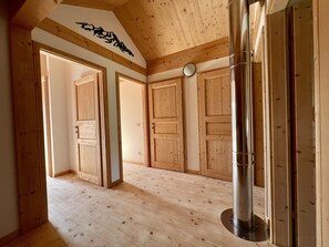 A room with wooden floors, a large metal column, and wooden doors.