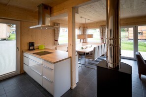 Et moderne køkken med en central ø, et spiseområde med et bord og stole, samt et stort vindue.