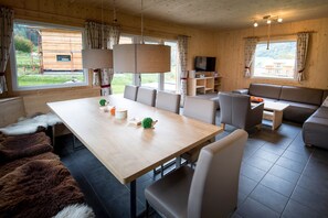 Un intérieur en bois comprenant une table à manger, des chaises, un canapé et un téléviseur.