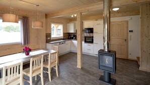 A modern kitchen with wooden cabinets, a built-in oven, and a wood-burning stove.
