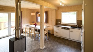 A modern kitchen with wooden cabinets, a dining area with a table and chairs, and a large window providing natural light.