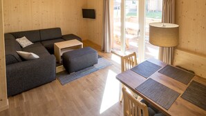 Un interior acogedor de cabaña de madera con un sofá, una mesita y una mesa de comedor con sillas.
