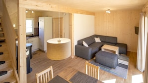 Un interior de madera con un sofá, una mesa de comedor y una zona de cocina.