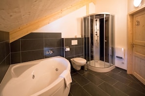 Et moderne badeværelse med badekar, toilet og brusekabine.