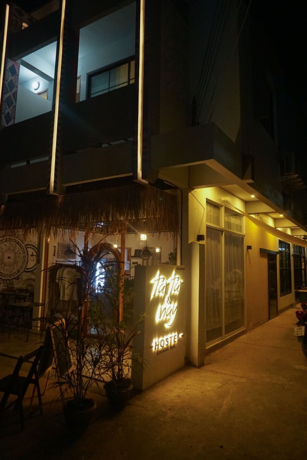 A hostel with a neon sign reading "Tarantula & Way HOSTEL" at night.