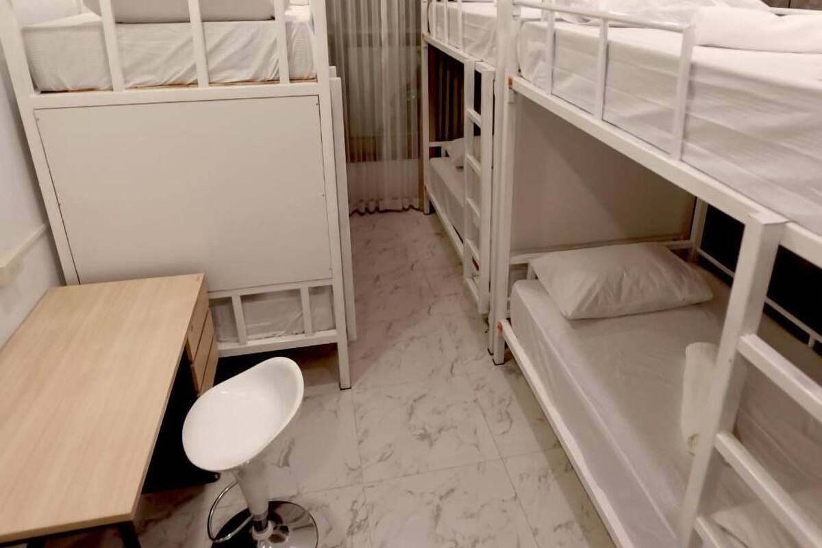 Una habitación pequeña y limpia con dos literas, una mesita y una silla.