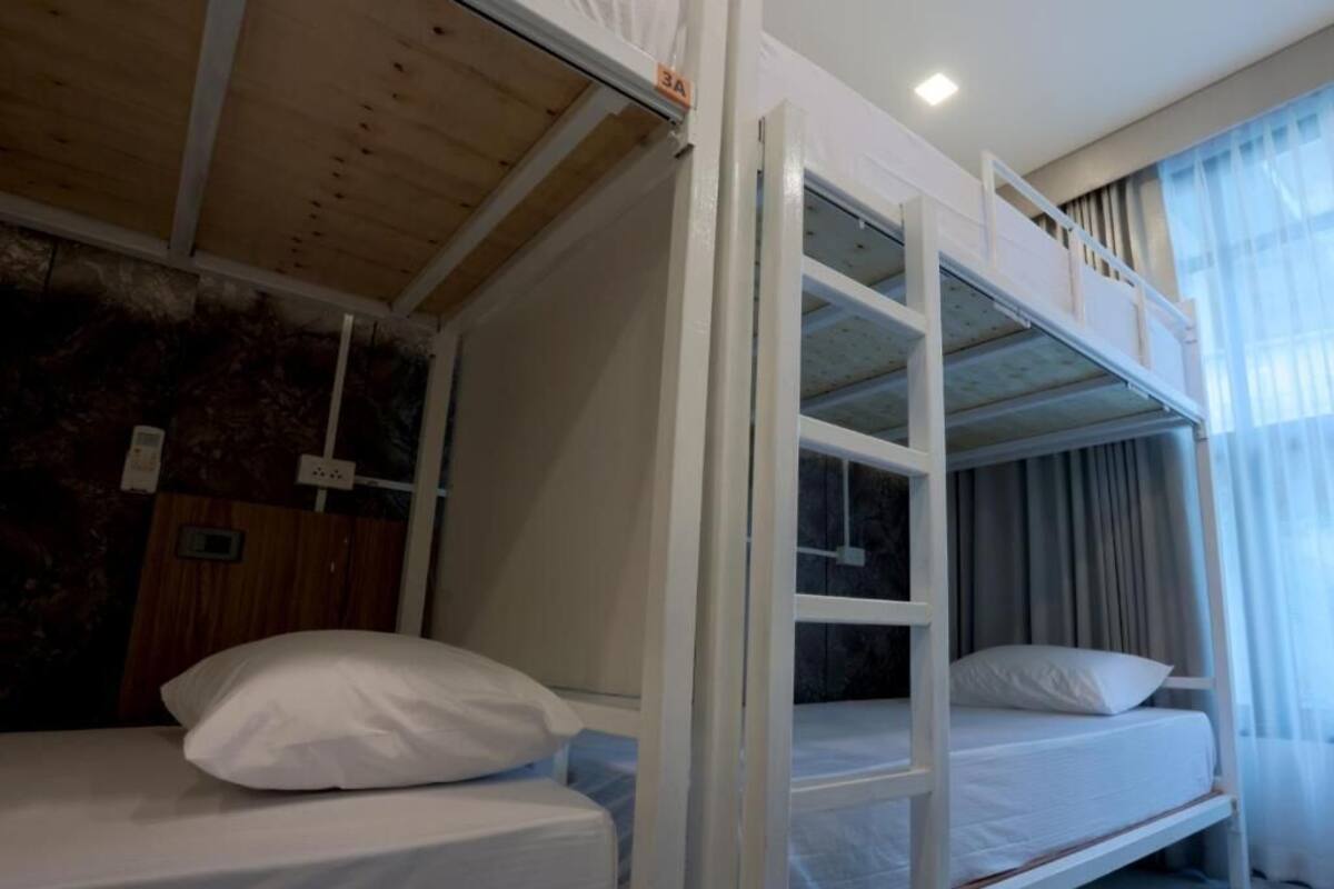 Dormitorio con literas, techo de madera, estructura de cama blanca y ventana con cortinas.