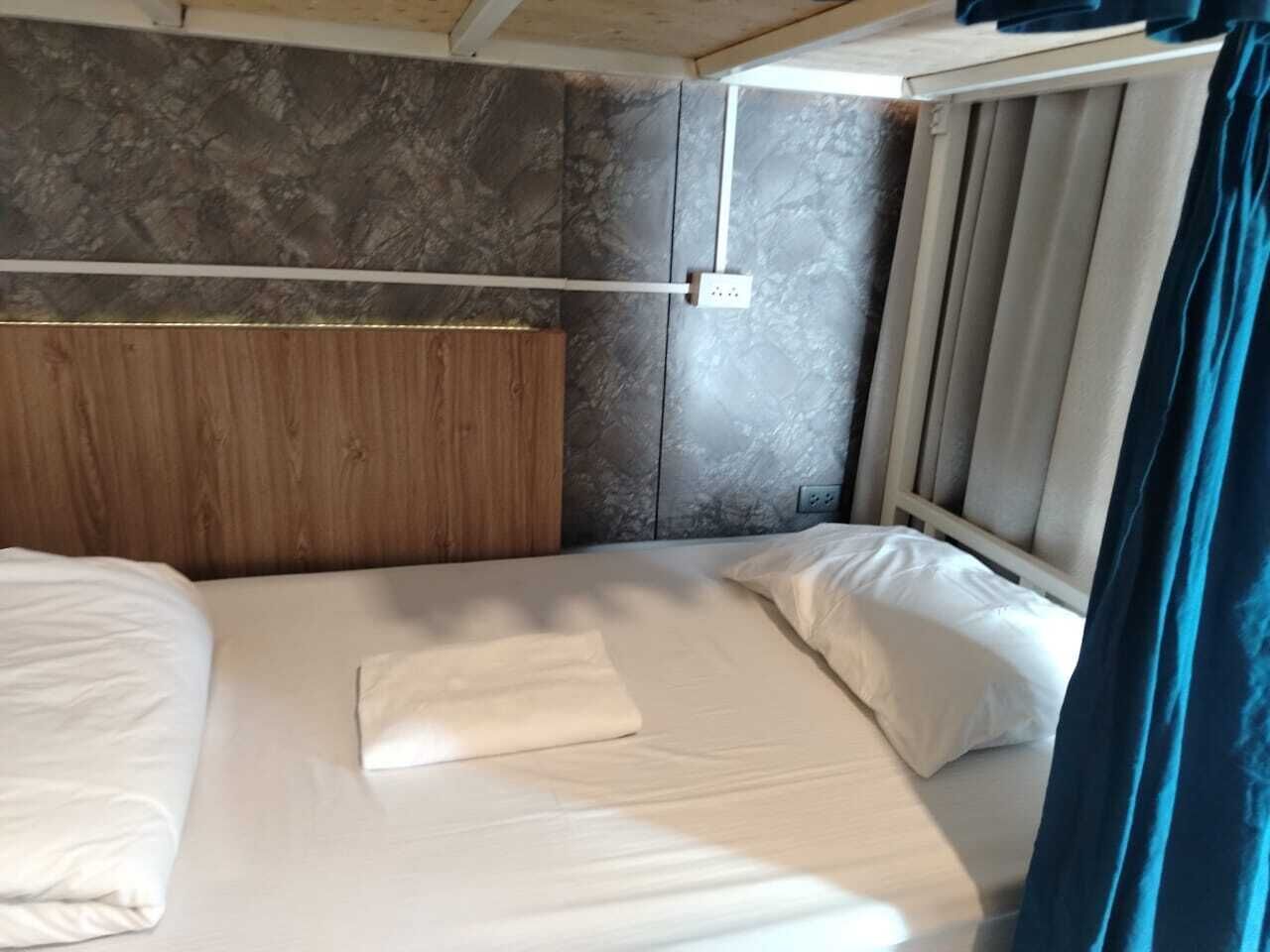 A single bed with a wooden headboard, a white pillow, and a folded white towel.