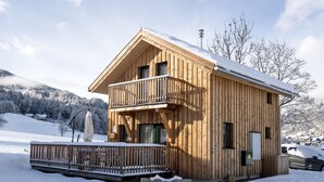 A wooden chalet with a balcony, surrounded by snow.