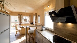 A modern kitchen with a built-in stove, wooden cabinets, and a dining area with a table and chairs.