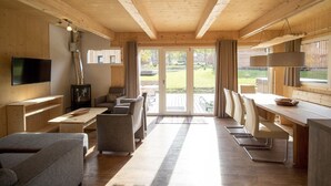 Un interior moderno con vigas de madera, un televisor, una chimenea y un comedor con sillas y una mesa.