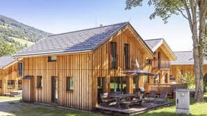 A wooden cabin with a balcony, outdoor seating, and a picnic table.