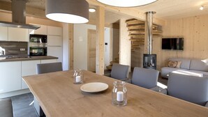 A modern kitchen with stainless steel appliances, a dining area with a wooden table, and a cozy living space with a fireplace.