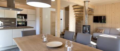 Una cocina moderna con electrodomésticos de acero inoxidable, un comedor con mesa de madera y una sala de estar acogedora con chimenea.
