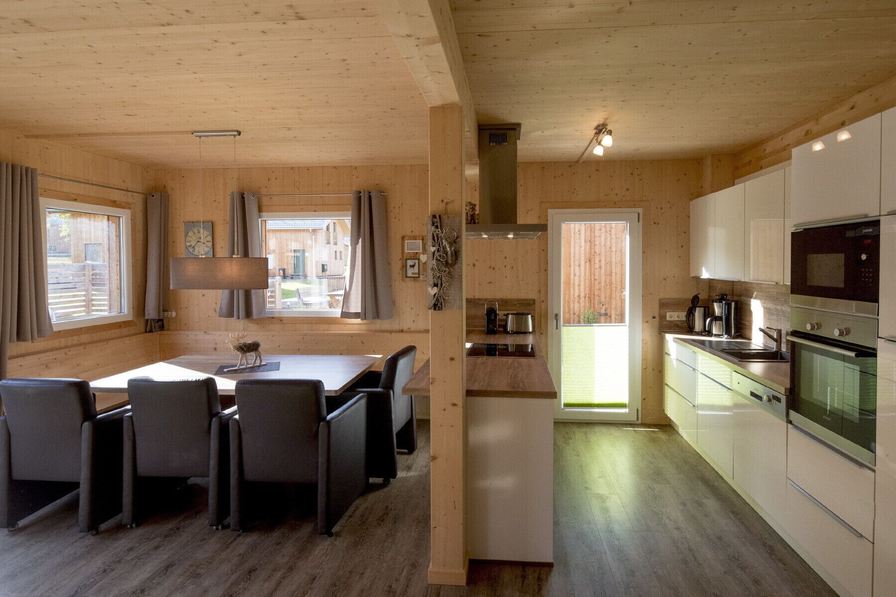 Una cabaña de madera acogedora con comedor, cocina y vistas al exterior.