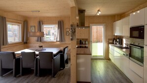Une charmante cabane en bois dotée d’un coin repas, d’une cuisine et offrant une vue sur l’extérieur.
