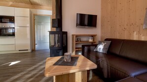 Un salon chaleureux avec un canapé en cuir marron foncé, une table basse en bois et un téléviseur fixé au mur.