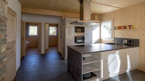 A modern kitchen with wooden walls, a central island, and built-in appliances.
