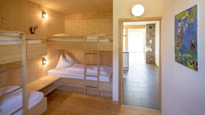 A wooden cabin with bunk beds, a stone wall, and a colorful painting.