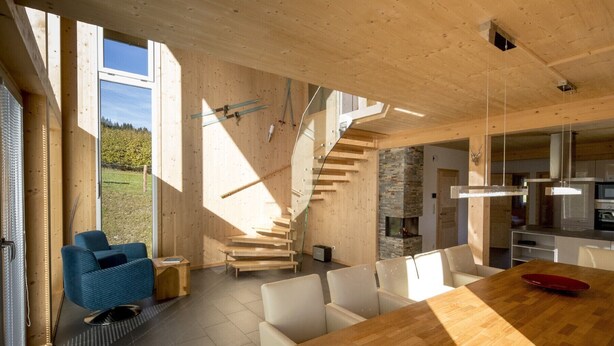 A modern interior with a wooden staircase, a dining area, and a kitchen.