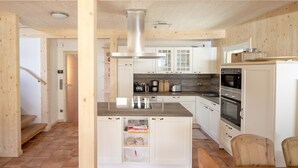 A modern kitchen with white cabinets, a central island, and built-in appliances.