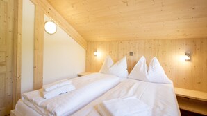 A wooden-paneled room with a bed, two wall-mounted lights, and a round light fixture on the wall.