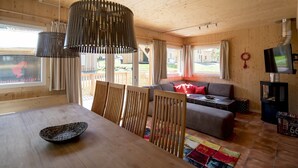 A cozy cabin interior with a dining area, sofa, and television.