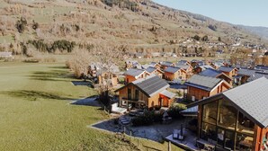 A cluster of wooden cabins with sloped roofs, arranged in a row on a hillside.