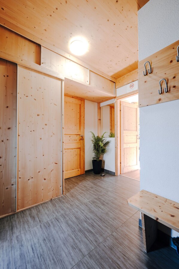 A wooden interior with a bench, a potted plant, and a wall-mounted hook.