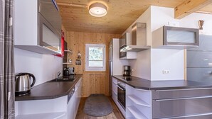 A compact kitchen with modern appliances, wooden walls, and a small window.