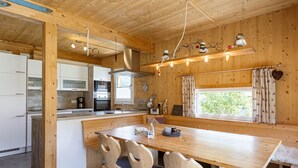 Puisesti sisustettu tila, jossa on keittiö, ruokailutila ja suuret ikkunat.