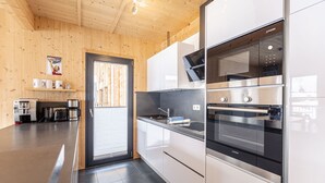 Una cocina moderna con paredes de madera, electrodomésticos de acero inoxidable y encimera negra.