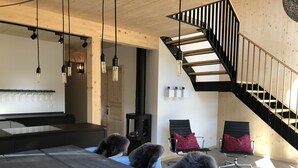 A modern interior with a wooden dining table, chairs, a black staircase, and a fireplace.
